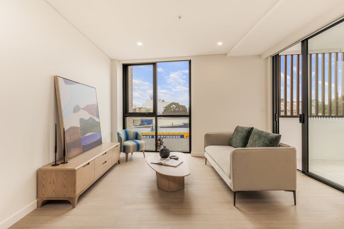 Furnished one bedroom living room at Arte Living Caringbah with lounge, media console and floor-to-ceiling window