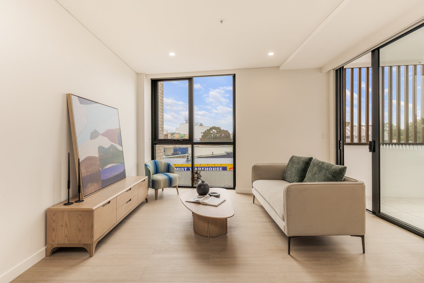 Furnished one bedroom living room at Arte Living Caringbah with lounge, media console and floor-to-ceiling window