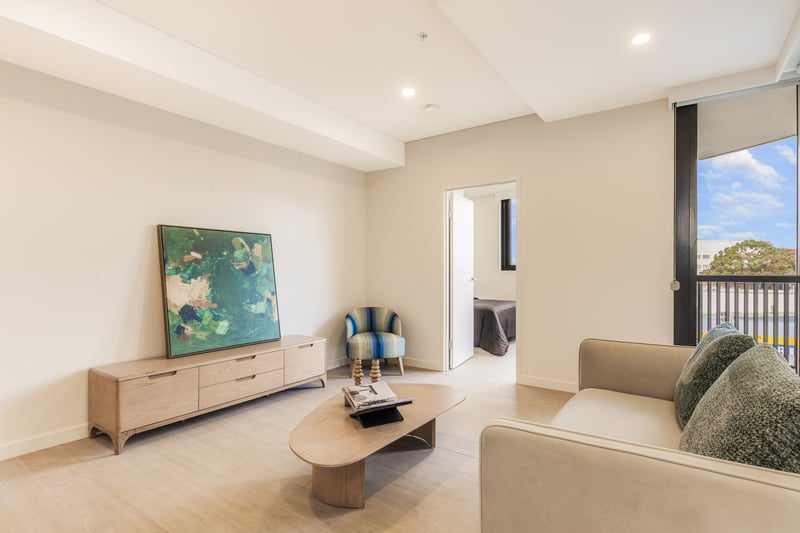 Furnished two bedroom living room at Arte Living Caringbah opening to a bedroom and balcony