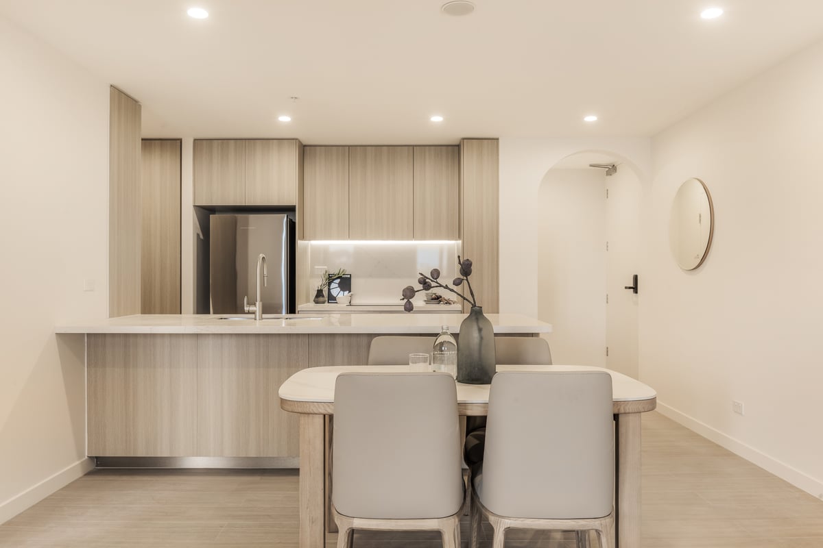 Two bedroom kitchen with island bench and dining table for four at Arte Living Caringbah