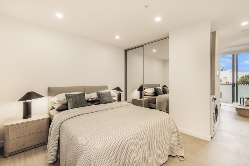 Studio sleeping area at Arte Living Caringbah with mirrored wardrobe and in-unit laundry