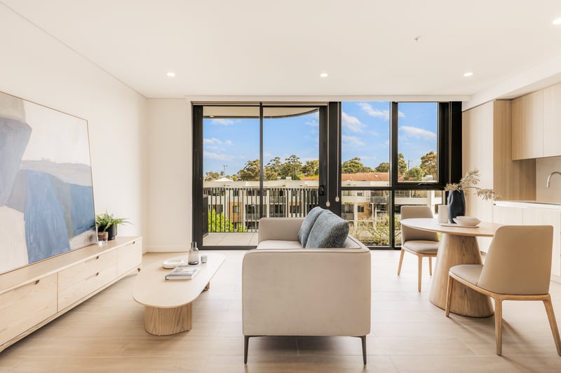 Light-filled studio living area at Arte Living Caringbah with lounge, dining setting and balcony views