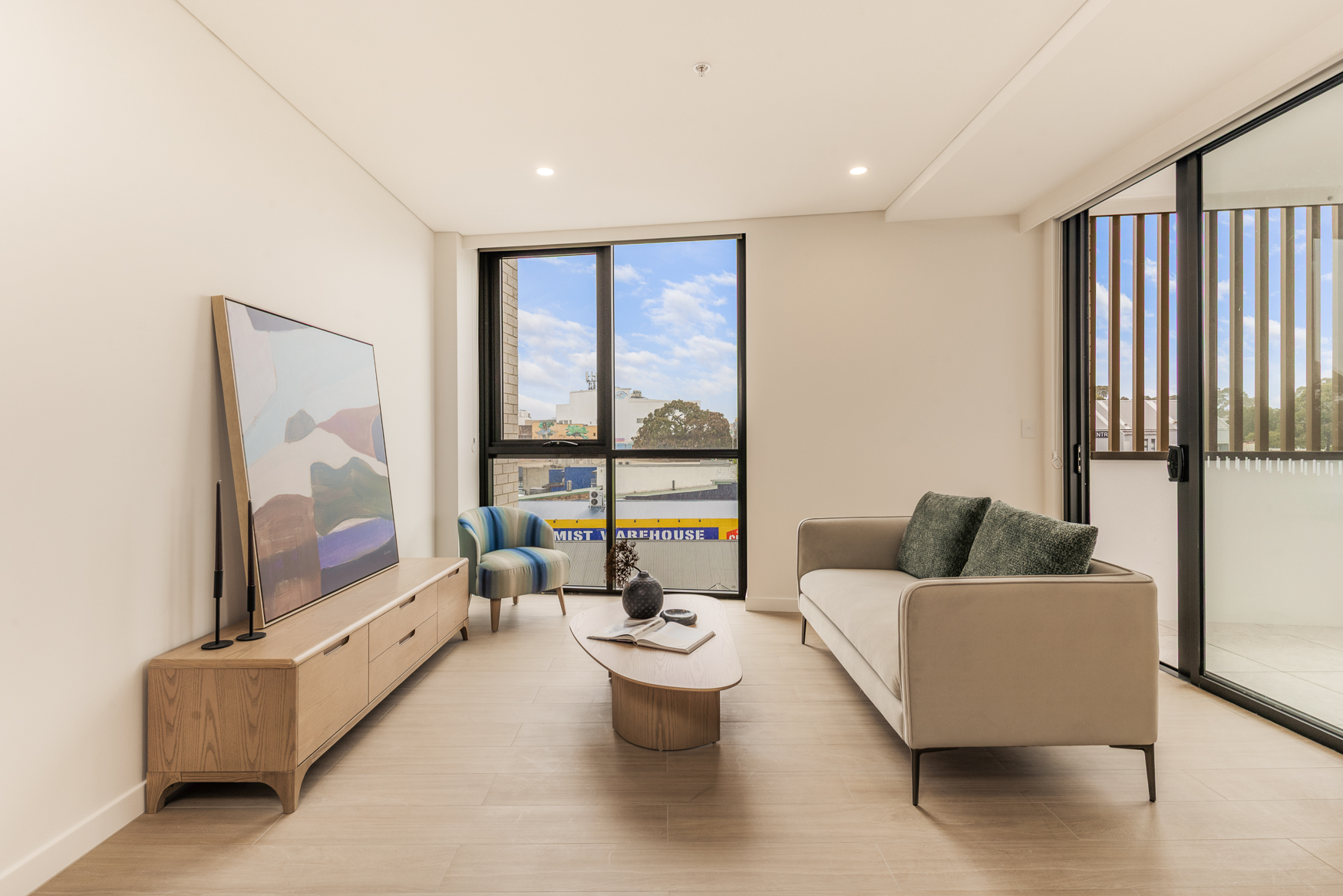 Furnished one bedroom living room at Arte Living Caringbah with lounge, media console and floor-to-ceiling window