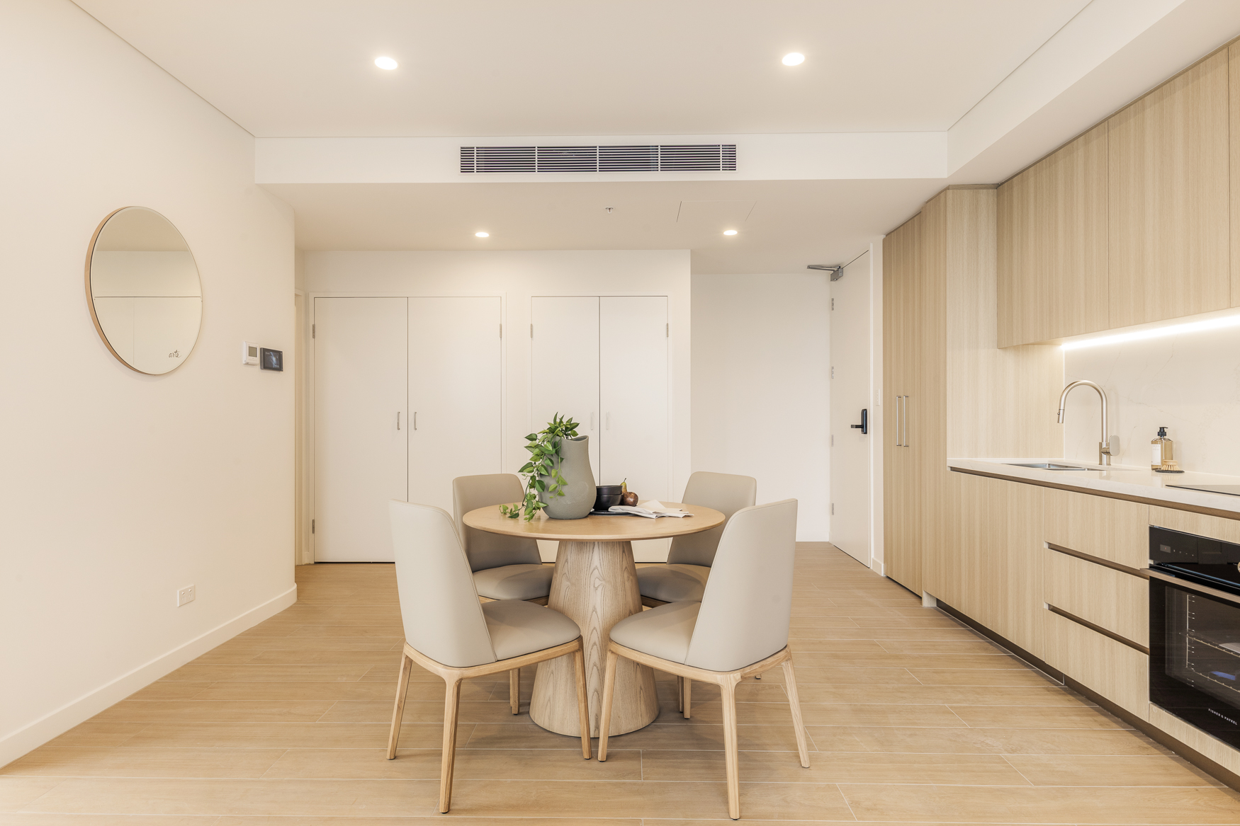 One bedroom dining area at Arte Living Caringbah with round table for four beside the kitchen