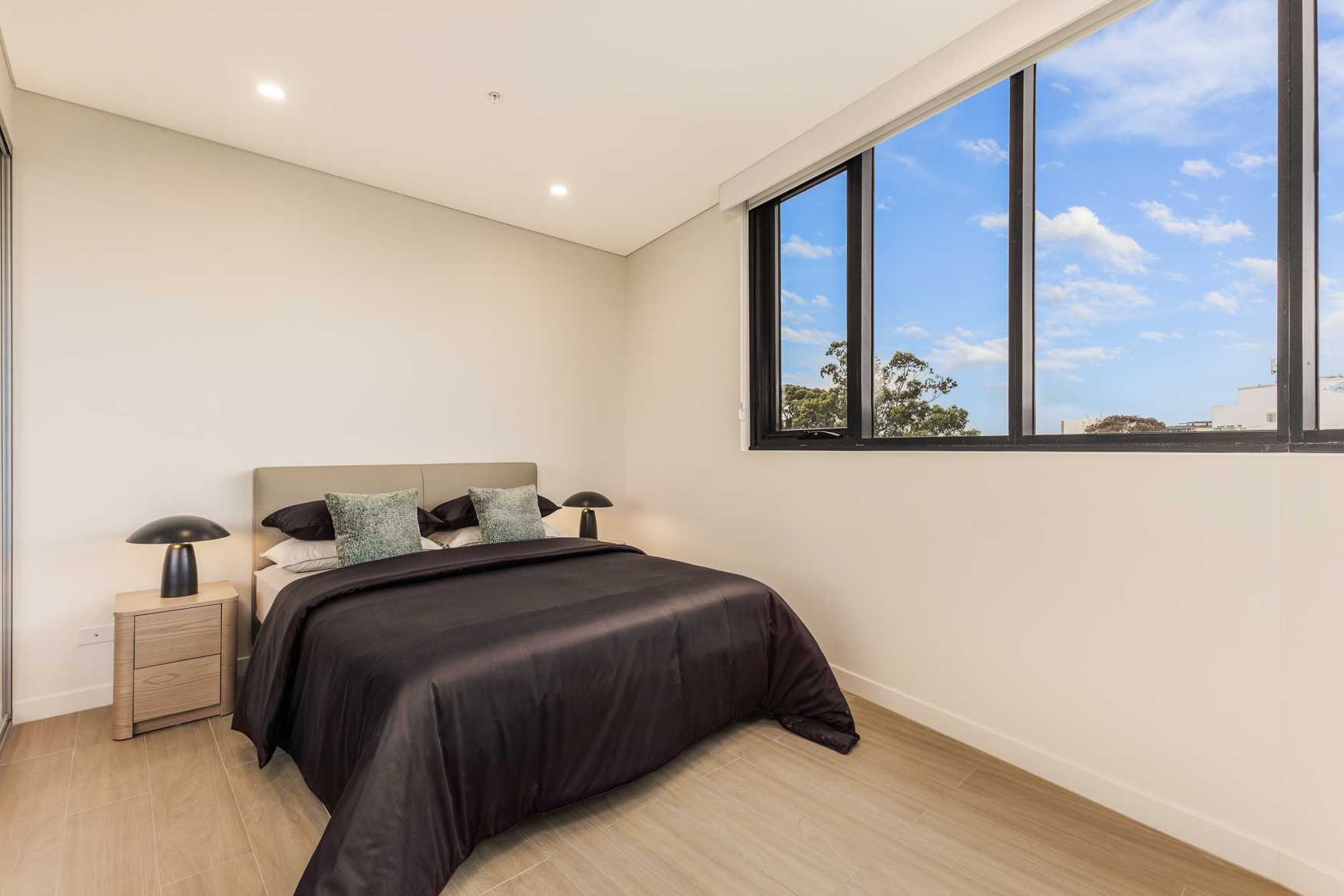 Second bedroom with queen bed and wide window in an Arte Living Caringbah two bedroom apartment